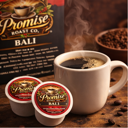 White mug with steaming coffee, 'Promise Roast Co.' Bali coffee packaging, and coffee beans on a wooden surface.